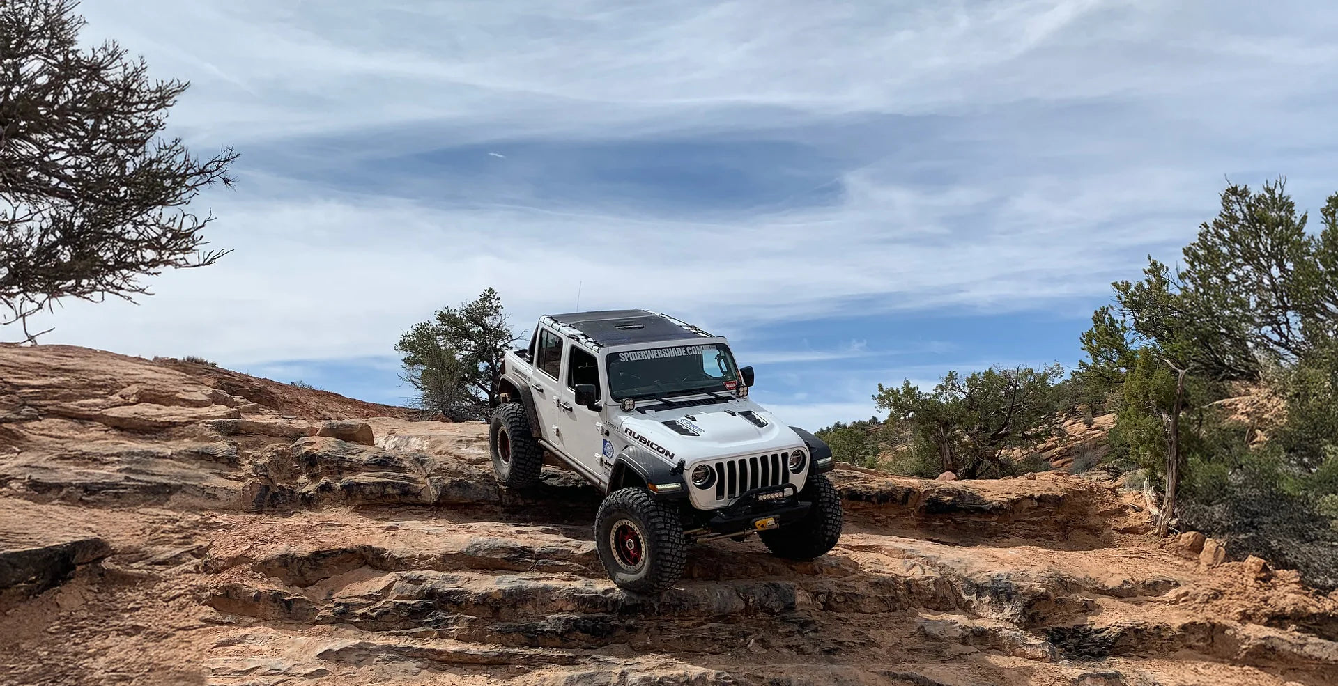 Jeep Wrangler JL 4-Door with mesh shade top installed on roll cage, parked on off-road trail