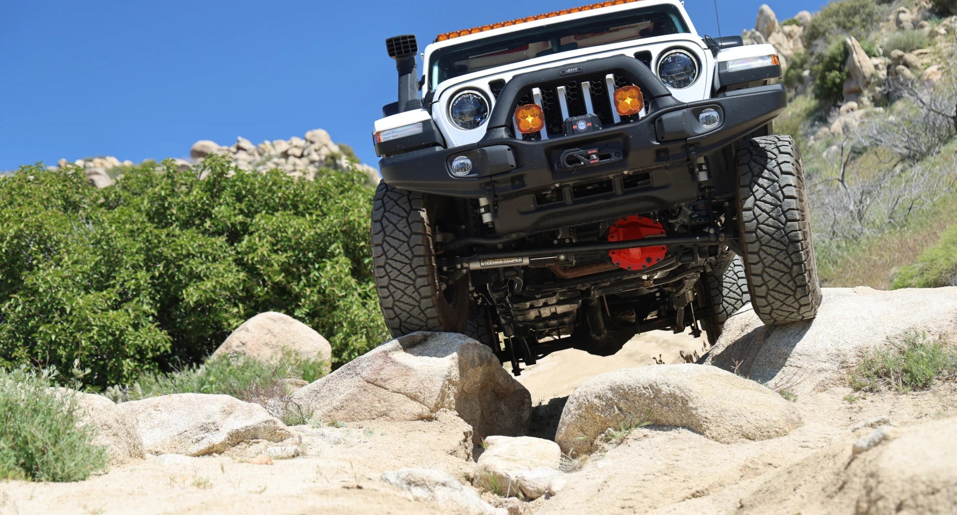 Jeep Gladiator JT with reinforced nodular-iron differential cover installed, showing rugged axle protection on rocky off-road terrain.